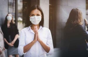 5 No Contact Greetings For Social Distancing From Around The World covid 19 contactless greeting lady wearing a mask and joining hands
